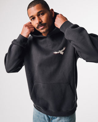 bunjil the wedged-tailed eagle hoodie in a washed out black color being worn in a front image displaying murrundindi eagle logo