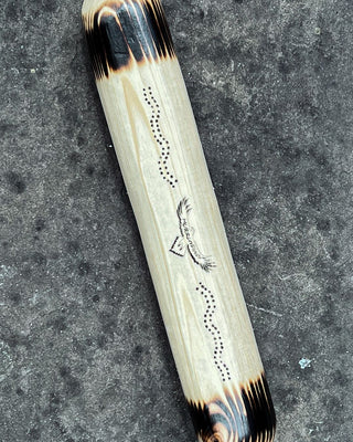 clap sticks indigenous instrument on top of each other on a rock showing details of pine wood and etched burn logo pattern details